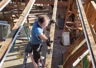 handyman on tall ladder, house demolition in progress